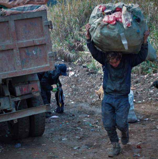 A waste worker carrying unloading waste from a waste truck